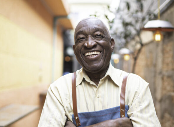Portrait of smiling elderly waiter looking at camera